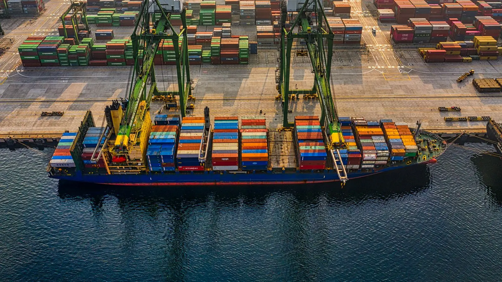 Container ship being loaded at a port at sunrise